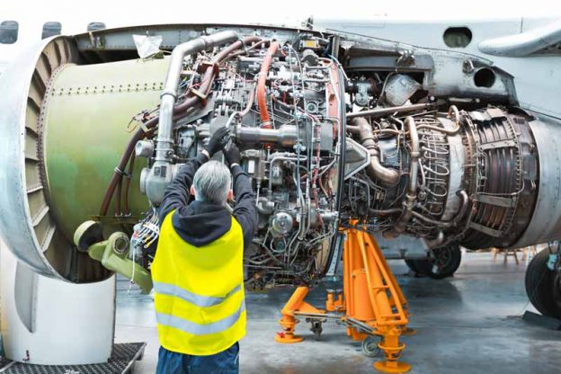 Aircraft mechanic repairing jet engine