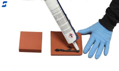 A red sponge shown having a tube of black RTV applied to the surface for bonding 